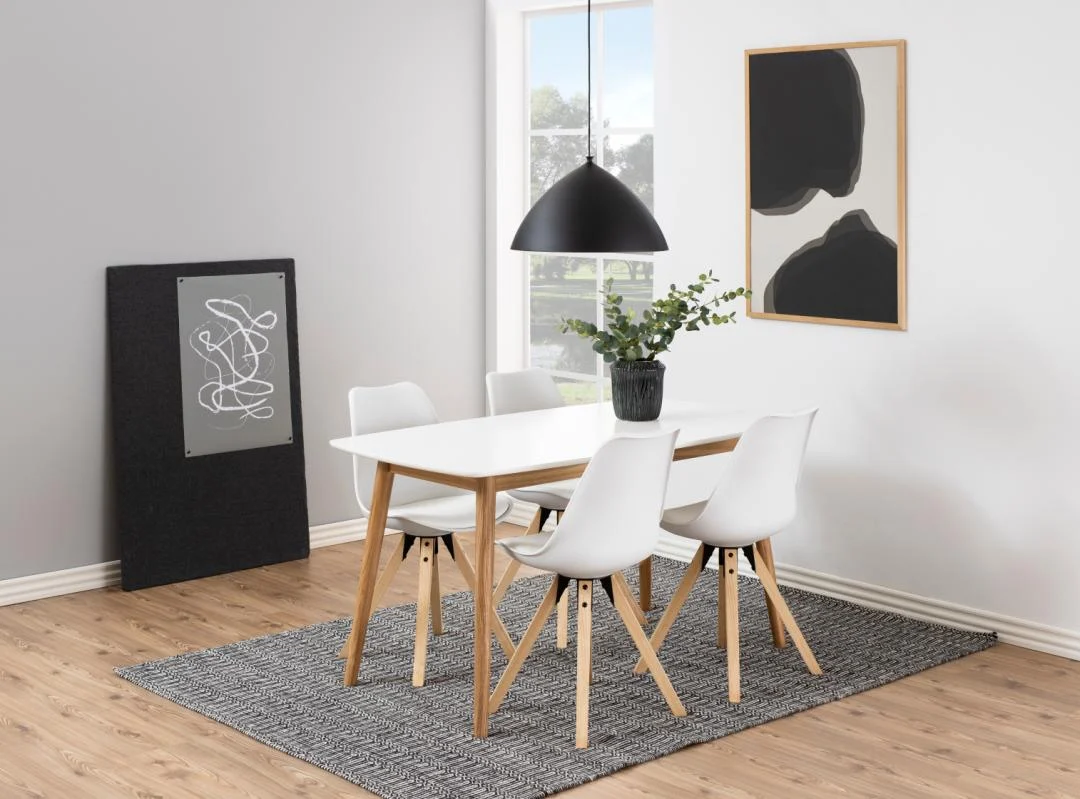 Een moderne eetkamer met de Eettafel Nieuwe Sfeer 150 x 80 CM rechthoekige eiken tafel, vier witte stoelen met houten poten, een zwarte hanglamp, een plantenpot, abstracte muurkunst en een vloerkleed op een houten vloer.