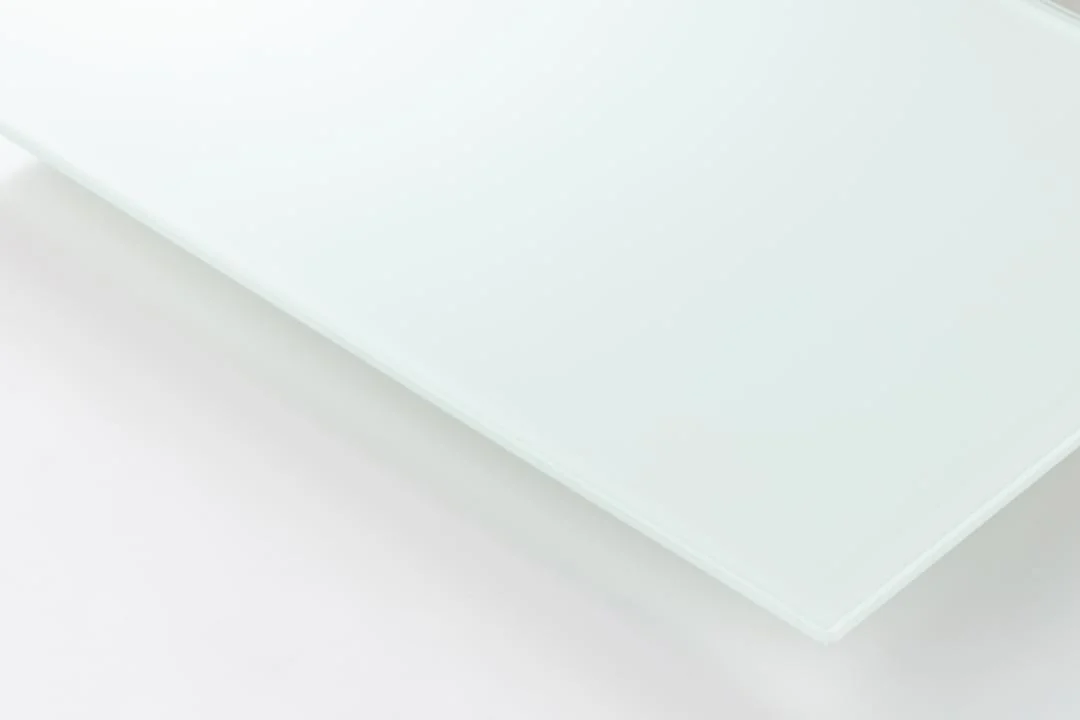 Een close-up van de Salontafel Wit 110 x 60 CM Rechthoek, gemaakt van glad kunststof, op een wit oppervlak, met zachte verlichting die de slanke rechthoekige vorm en oppervlaktestructuur benadrukt.