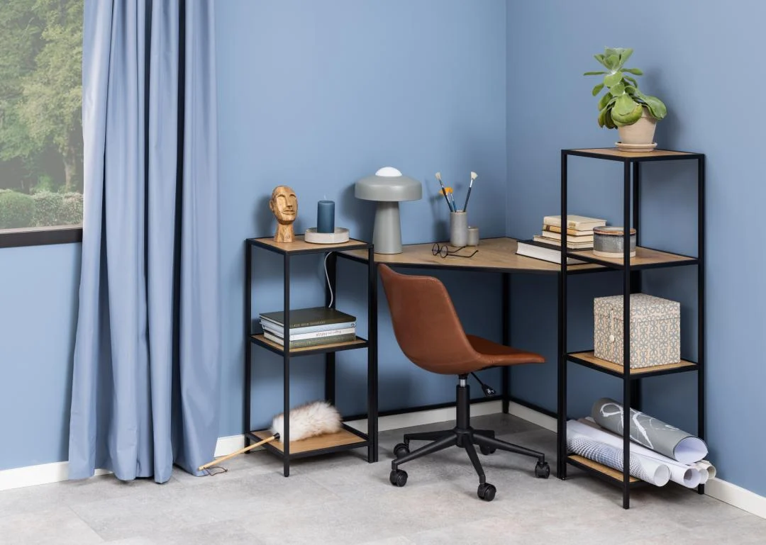 Hoekopname van een blauwe kamer met een industrieel bureau met een metalen frame en eikenhouten planken, inclusief een boekenkast met drie planken.