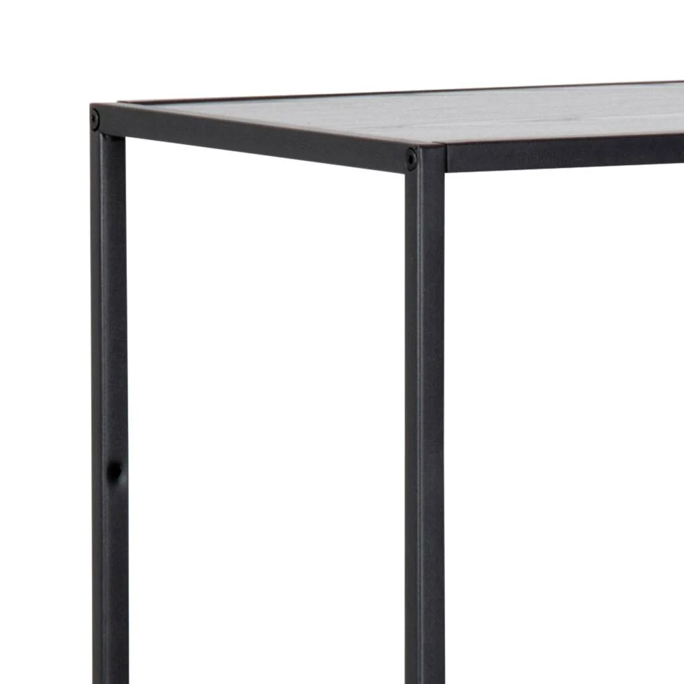 Een close-up van de hoek van de Seaford boekenkast, een minimalistisch zwart metalen rek met een rechthoekig blad en eenvoudige rechte poten, gefotografeerd tegen een effen witte achtergrond.