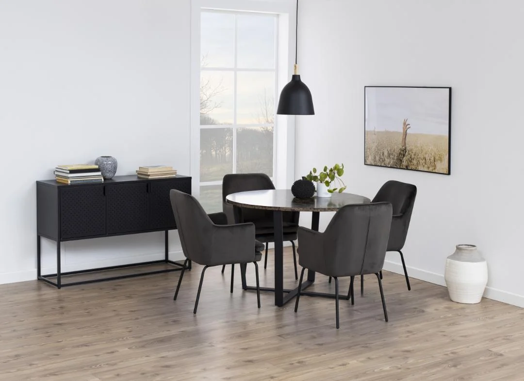 Een moderne eetkamer met de Eettafel Nieuwe Sfeer 110 CM Rond MDF Staal ronde tafel, vier zwarte stoelen, een zwart dressoir met decor, een hangende zwarte lamp, een plant, een raam en een ingelijste giraffefoto op de witte muur.