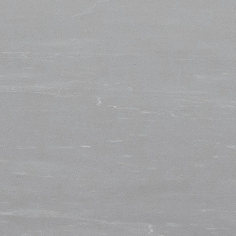 Een close-up van de Eettafel Amble Rond Marmer Metaal Mat toont het gladde, lichtgrijze marmeren tafelblad met subtiele witte adering en natuurlijke textuurvariaties, gecombineerd met een mat zwart metalen onderstel.