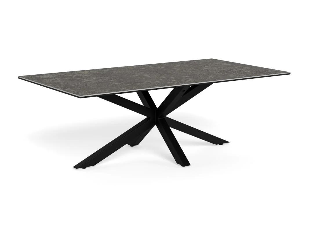 De Salontafel Zwart 130 x 70 CM Rechthoek heeft een rechthoekig blad van keramiek met een donkere, steenachtige afwerking en zwarte metalen poten die een geometrisch stervormig onderstel vormen.