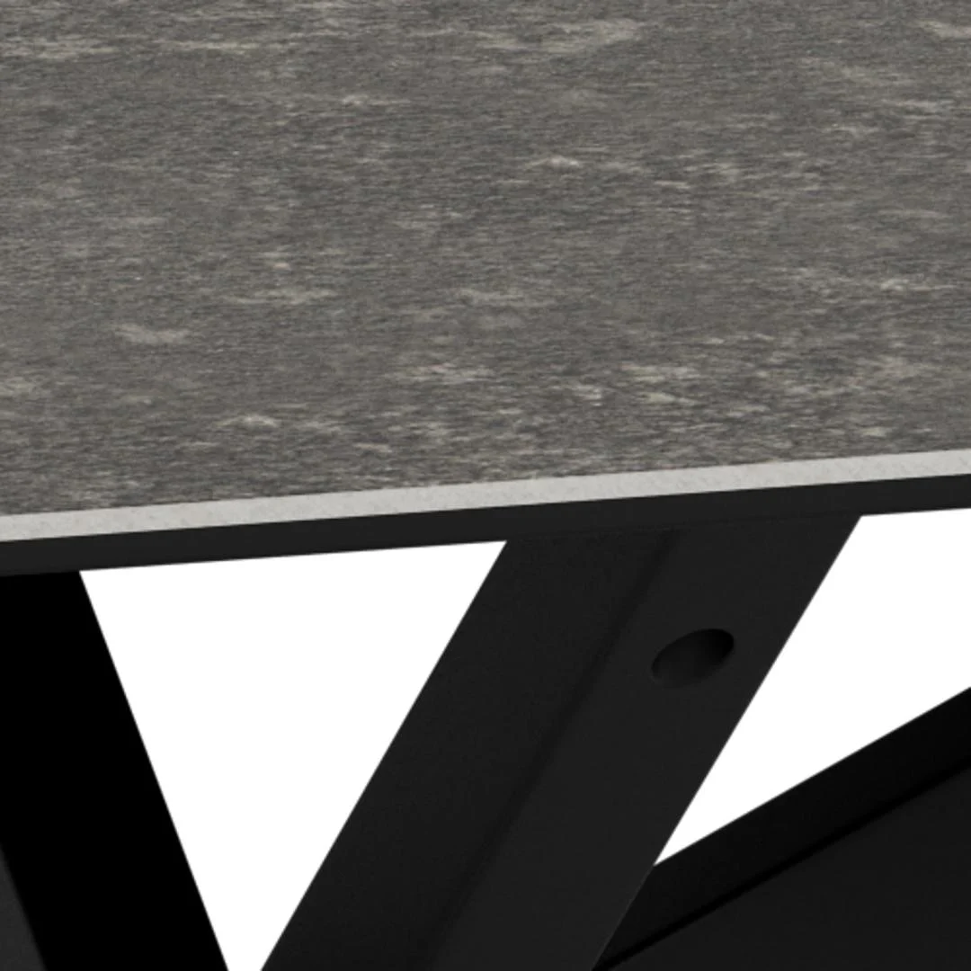 Close-up van Salontafel Zwart 130 x 70 CM Rechthoek: toont een grijs, gestructureerd keramiek tafelblad met afgeschuinde rand en zwarte metalen poten die elkaar eronder kruisen, tegen een witte achtergrond.