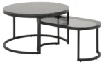 De Salontafel Rookglas bestaat uit twee moderne nesttafels met een zwart metalen onderstel: een met een rond donker massief blad en de andere met een ovaal zwart glazen blad dat gedeeltelijk onder de ronde tafel geschoven kan worden.
