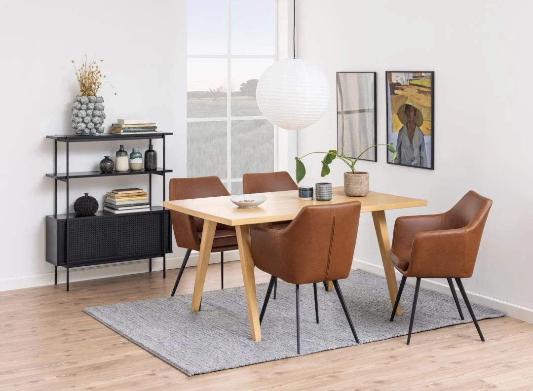 Een moderne eetkamer met een houten tafel, vier bruine stoelen, een grijs vloerkleed, een Angus boekenkast met decor, een plant, muurkunst en een grote ronde witte hanglamp bij een raam.
