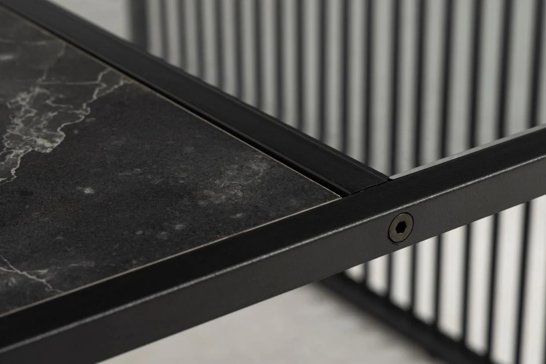 Close-up van de Salontafel Rookglas, Zwart 80 x 40 CM met een vierkant tafelblad van rookglas en een zwart metalen frame. Strakke lijnen en verticale metalen latten op de achtergrond benadrukken het moderne, minimalistische, industriële ontwerp.