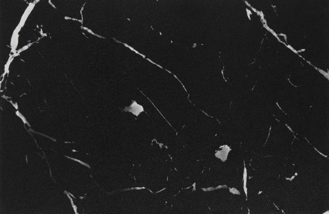 De Salontafel Zwart 60 x 60 CM Vierkant heeft een strak, glad en gepolijst zwart kunststof ontwerp met dunne witte aderen en kleine, onregelmatige witte vlekken voor een moderne, elegante uitstraling.