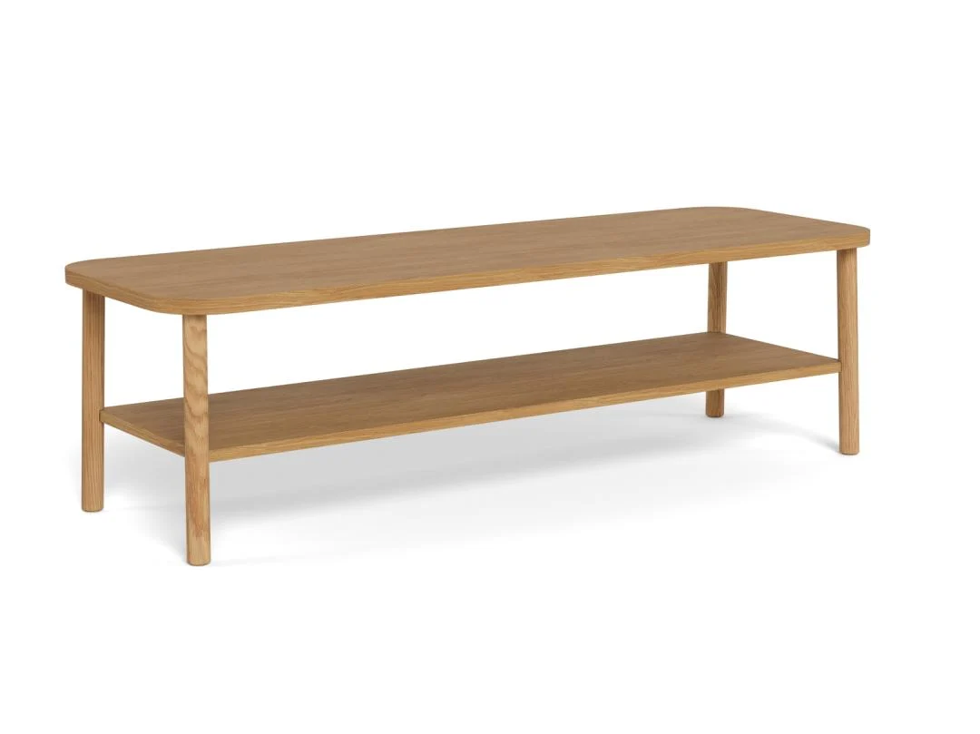 De Salontafel Roest is een ronde salontafel (134 x 34 cm) gemaakt van eikenfineer, met vier poten, een onderste opbergplank, afgeronde hoeken en een minimalistisch ontwerp met een natuurlijke houten afwerking.