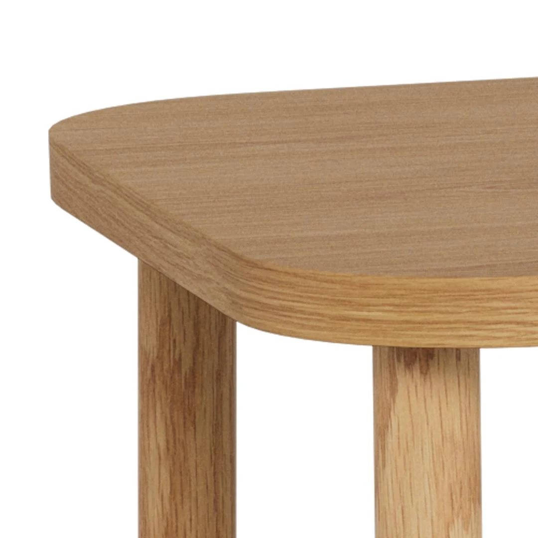 Close-up van de hoek van de Salontafel Roest 134 x 34 CM Rond, gemaakt van eikenfineer, met een gladde, ronde rand en natuurlijke houtnerfstructuur. Twee tafelpoten zijn gedeeltelijk zichtbaar onder het tafelblad.