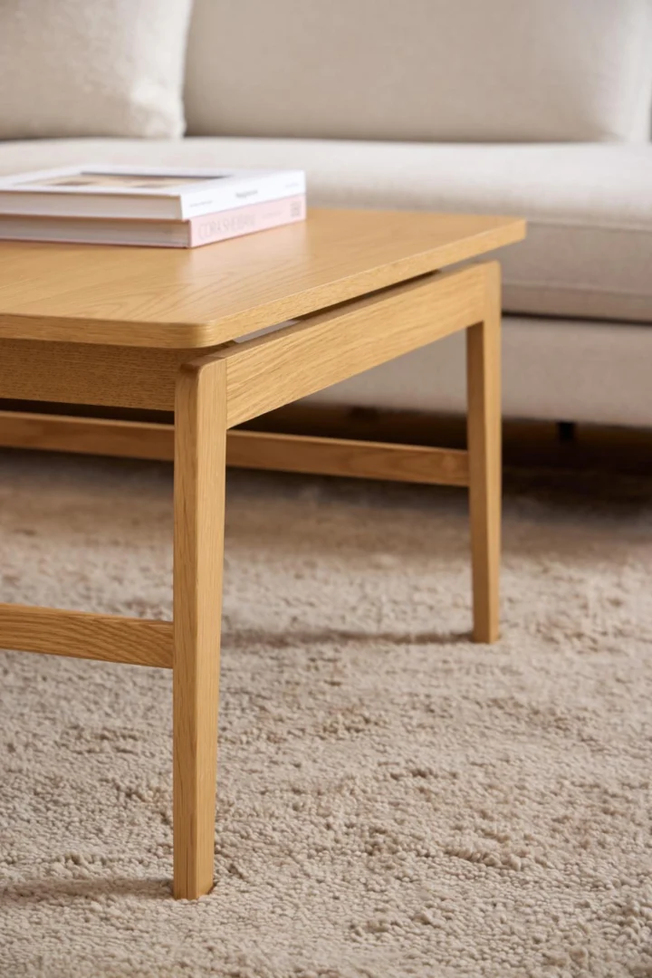 De Salontafel 80 x 80 CM Rechthoek in eikenfineer ligt op een beige vloerkleed met een witte bank op de achtergrond en twee gestapelde boeken op tafel.