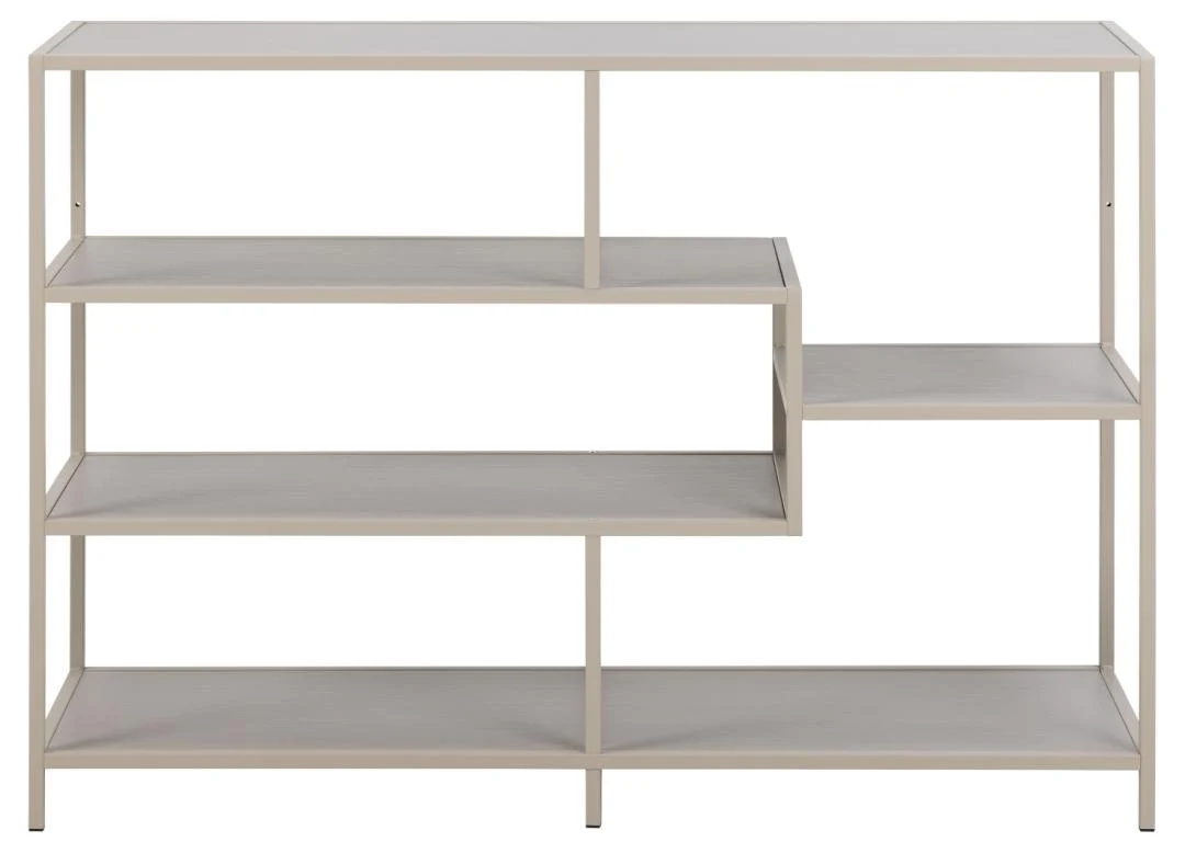 De Seaford boekenkast is een moderne, lichtgrijze metalen boekenkast met vier planken van verschillende lengte in een asymmetrisch, geometrisch ontwerp, met een getrapte rechterkant die twee kortere planken bevat.