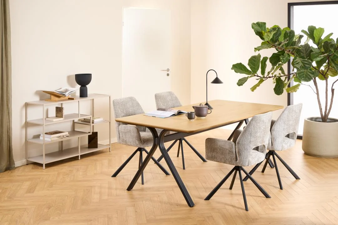 Een moderne eetkamer met een houten tafel, vier grijze stoelen met kussens, een potplant, de Seaford boekenkast met decoratieve items en een theepot op tafel. De ruimte heeft lichte muren en houten vloeren.