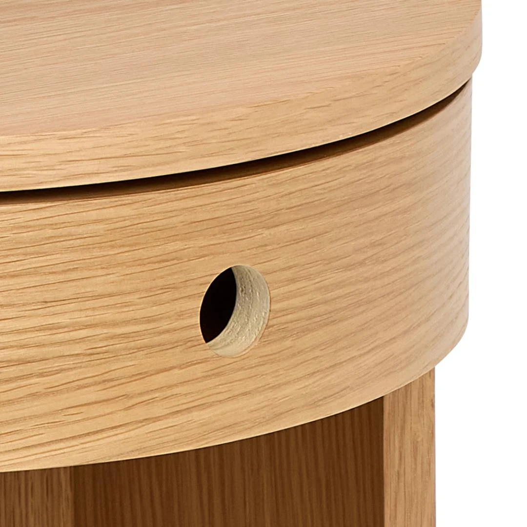 Close-up van het Nachtkastje Eikenhout Slaapkamer, met de licht eiken afwerking, de ronde vorm en de ronde uitsparing aan de zijkant die de houtnerf en het gladde oppervlak benadrukt.