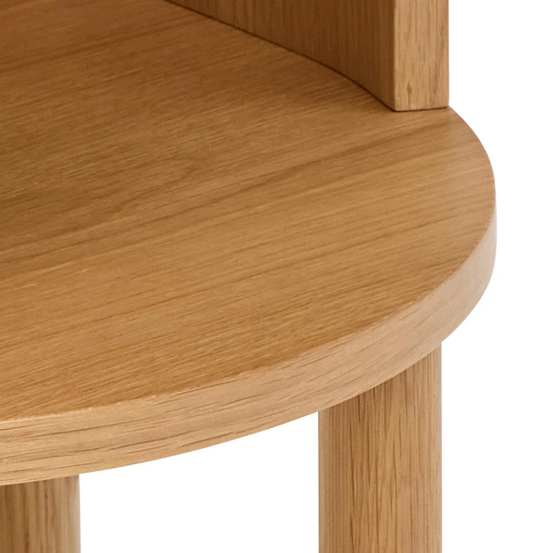 Close-up van het Nachtkastje Eikenhout Slaapkamer: een licht eiken nachtkastje met een ronde rand, cilindrische houten poten, zichtbare natuurlijke nerf en een gladde minimalistische afwerking.
