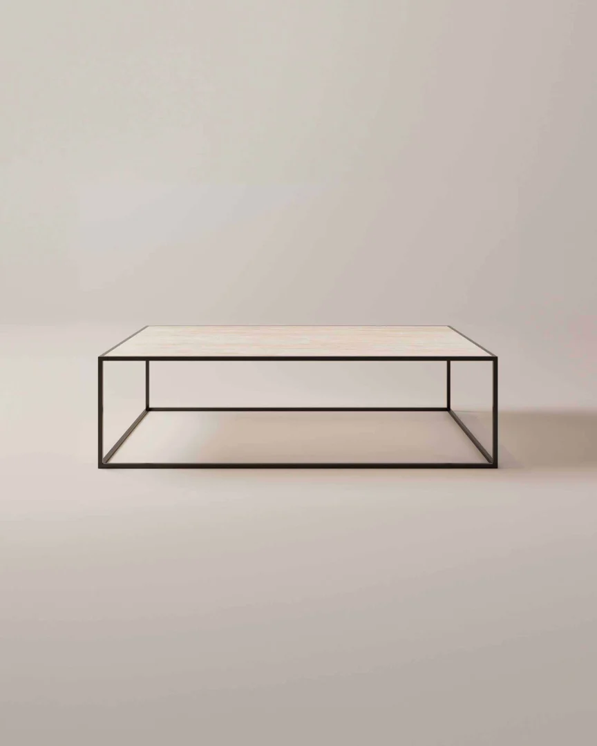 De Salontafel Zwart Klassiek Tijdloos Design heeft een minimalistisch rechthoekig blad van licht hout en een slank zwart metalen frame, tegen een effen, lichte achtergrond.