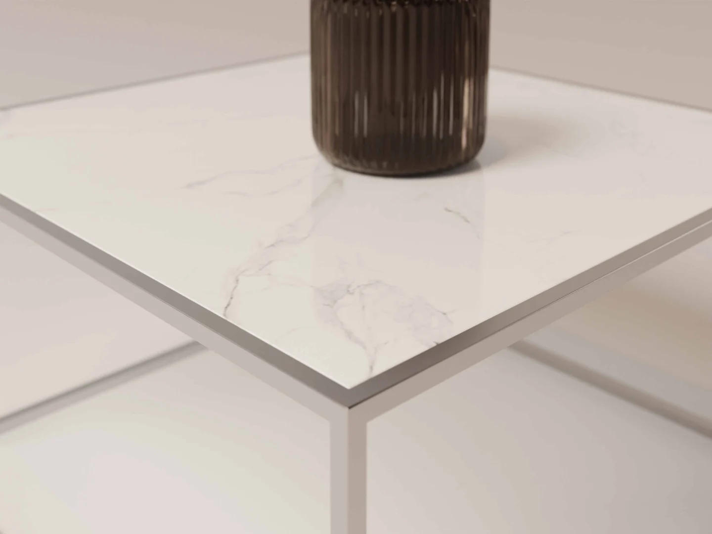 De Salontafel Zilver Scandinavisch, met een wit marmeren blad en een slank metalen frame, ondersteunt een donkere geribbelde vaas. Alleen de hoek van de tafel en de basis van de vaas worden getoond tegen een minimale, neutrale achtergrond.