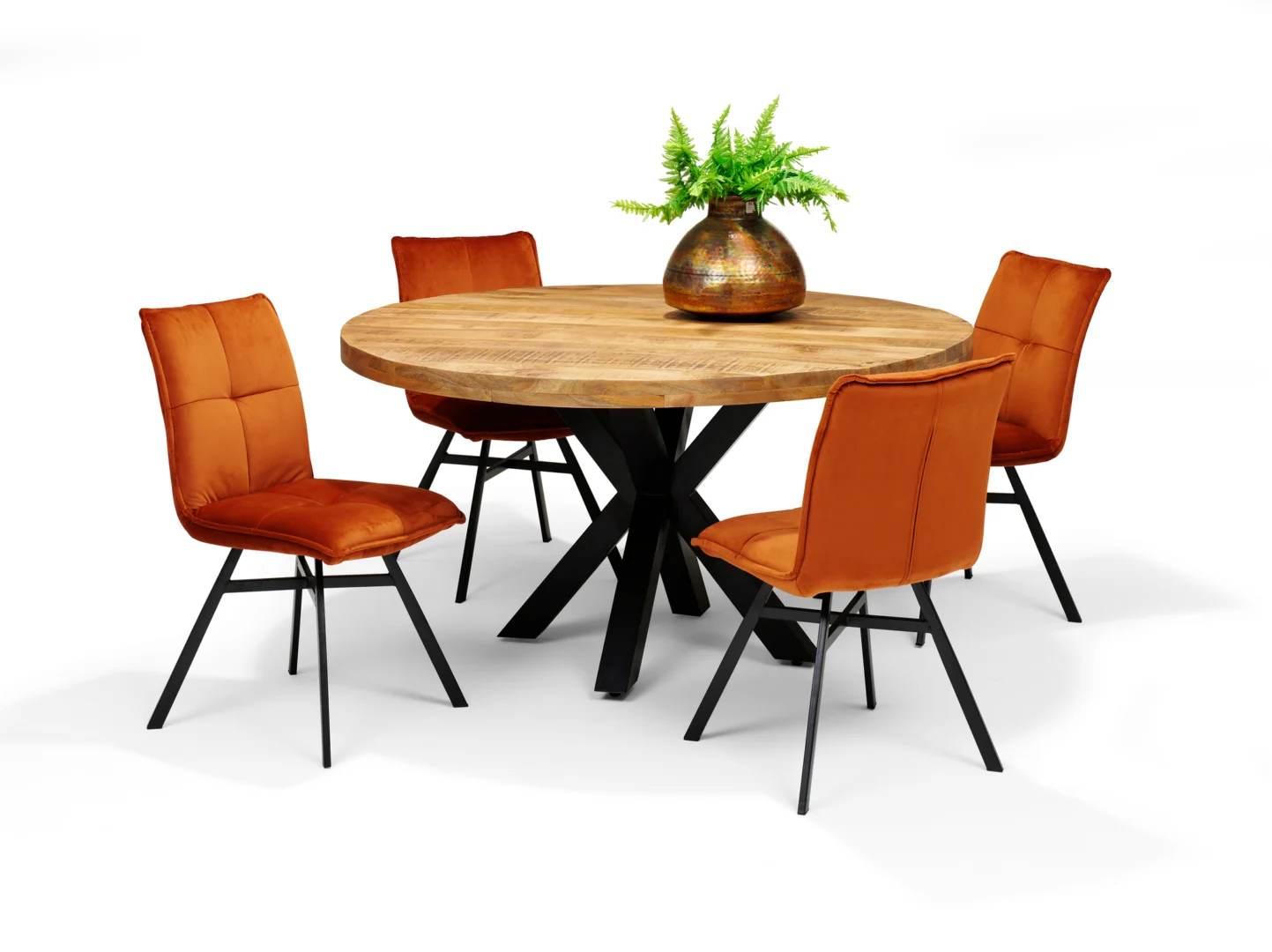 De Eettafel SPIDER Mango - 150 Rond, een ronde houten eettafel met een zwart metalen onderstel, is gecombineerd met vier oranje gecapitonneerde stoelen met zwart metalen poten. Een bruine vaas met groene varens siert het midden van de tafel.