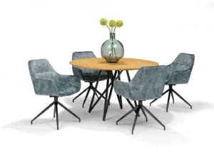 De Triton Eetkamertafel 130 rond Mango Naturel is een ronde houten eettafel, afgebeeld met een glazen vaas met groene bloemen in het midden en omringd door vier blauw gestoffeerde stoelen met zwart metalen poten op een witte achtergrond.