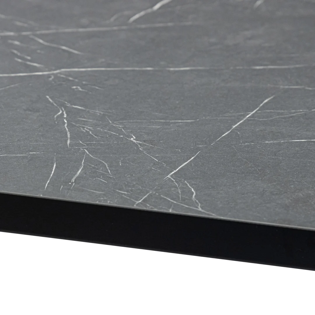 Een close-up van de Stalux Eettafel 'Gijs' 180 x 100cm in zwart/zwart marmer, met de nadruk op het donkergrijze matte marmeren oppervlak met dunne witte adering en de rand van de tafel.