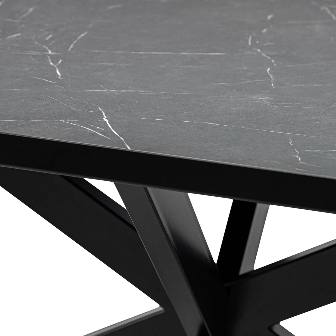 Een close-up van de Stalux Eettafel 'Gijs' (180 x 100 cm) met een zwart marmeren blad en zwarte metalen poten in een hoekig, geometrisch ontwerp.