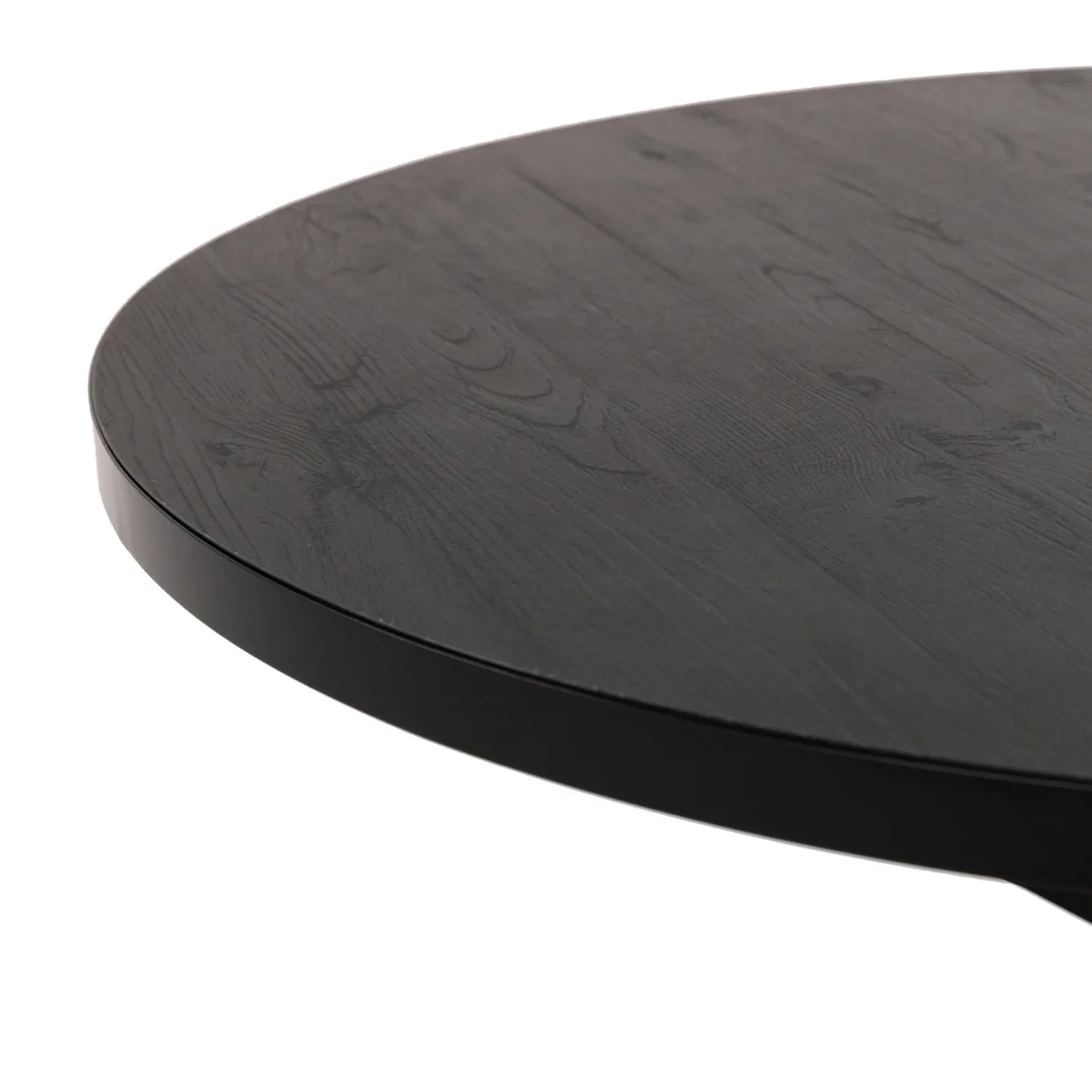 Close-up van de rand van de Stalux Ronde eettafel 'Daan' 135cm in zwart/zwart eiken, die het gladde, ronde donkerhouten tafelblad en de zichtbare houtnerfstructuur laat zien.