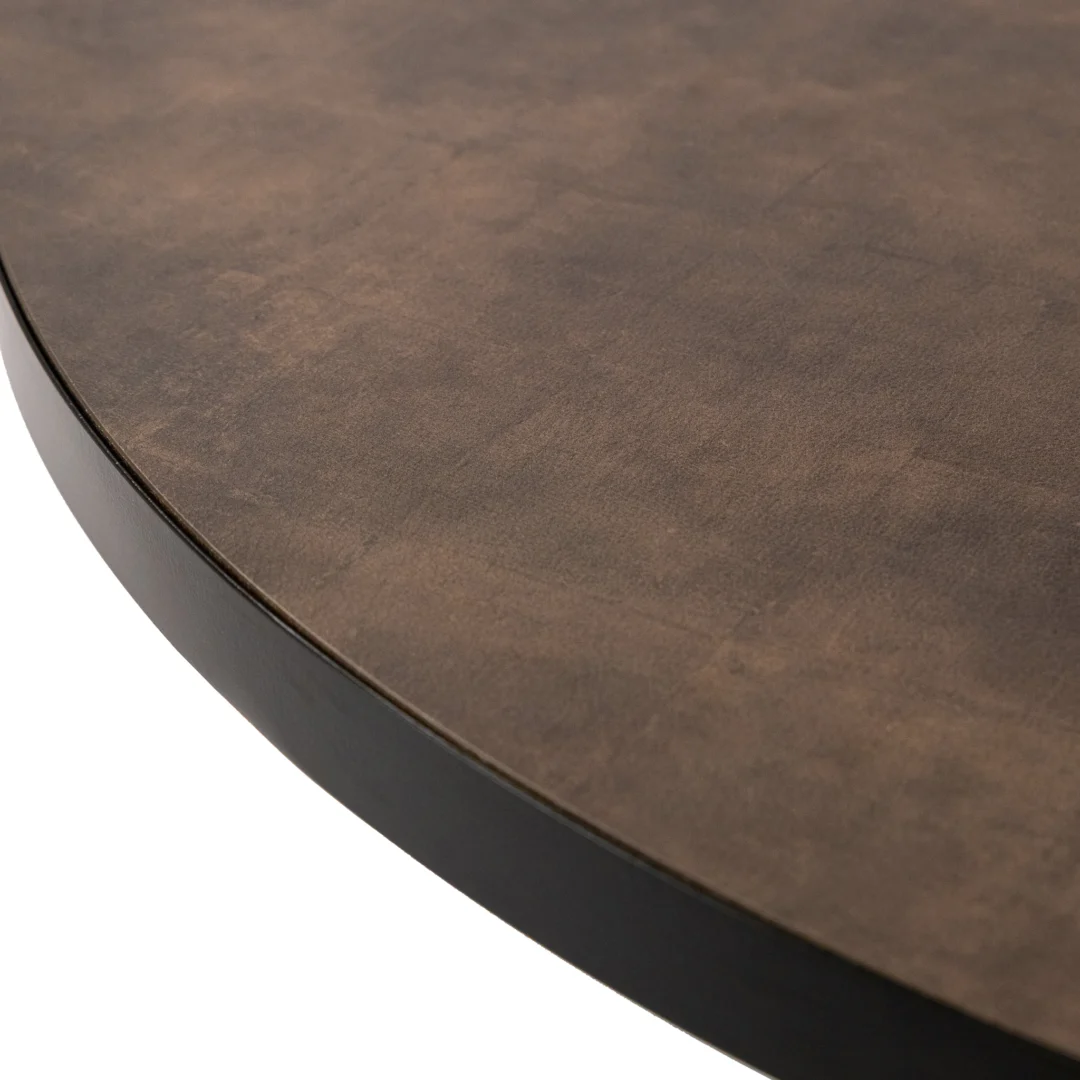 Close-up van de rand van de Stalux Ronde eettafel 'Daan' 135cm in zwart met een lederlook bruin, gestructureerd oppervlak en een gladde, donkere rand.