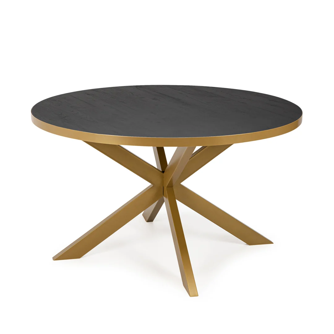 De Stalux Ronde eettafel 'Daan' (135cm) heeft een zwart eikenhouten rond blad en een goud metalen onderstel met vier schuine poten die elkaar in het midden kruisen.
