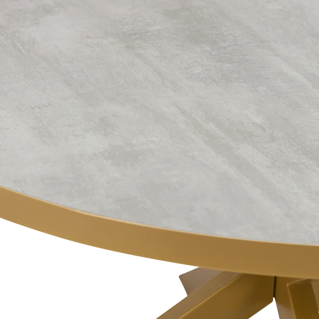 Een close-up van de Stalux Ronde eettafel 'Daan' (148cm) met een gouden onderstel en rand en een betonnen lichtgrijs tafelblad.