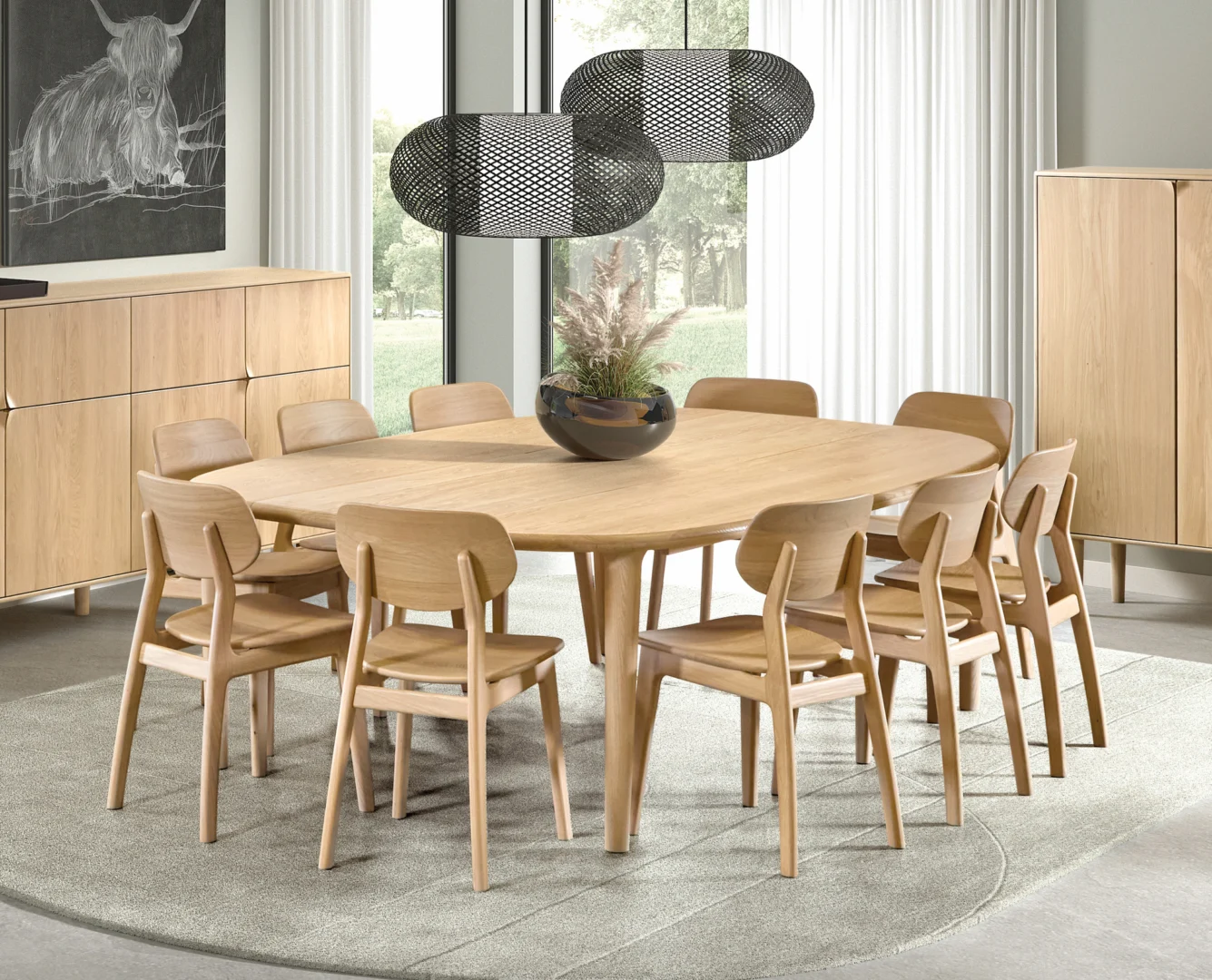 Een moderne eetkamer met de SENTO TAFEL 240 X 108/164 E02M, omringd door acht bijpassende houten stoelen, met een middenstuk van pampagras en hanglampen van zwart gaas. Licht houten meubilair en transparante gordijnen maken de look compleet.