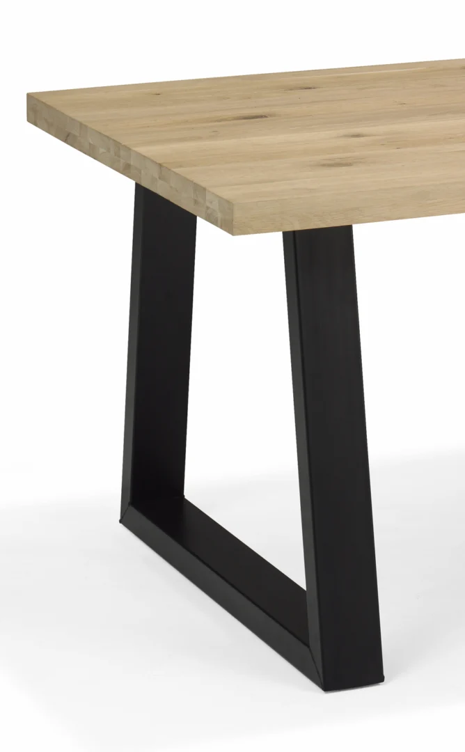 Een close-up van de FRAME DELTA-POOT 120X60X74 ZWART toont het lichthouten tafelblad en de geometrische zwarte metalen poot tegen een witte achtergrond.