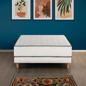 Witte boxspring 180 x 200 met ventilerend matras, zwarte bies, houten poten en een blauwe muur met kunst aan de wand op een lichte houten vloer.