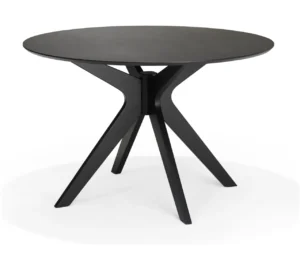 De Julia 120x120 Eettafel Rond Eiken Zwart is een moderne ronde tafel van zwart eiken met een glad blad en vier schuine poten die elkaar in het midden kruisen en een X-vormig onderstel vormen.