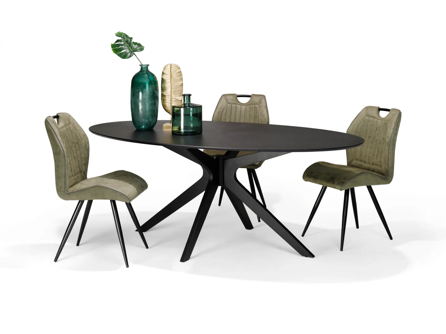 De Julia 200X110 Eettafel Ovaal Zwart Eiken, een moderne ovale zwarte eettafel met schuine poten, is gekoppeld aan vier groen gestoffeerde stoelen. Groene glazen vazen en een blad sieren het tafelblad tegen een witte achtergrond.
