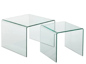 De Bijzettafel Transparant 65 x 65 CM bestaat uit twee vierkante nesttafels van helder glas met metalen frame en gebogen randen, één groter en één kleiner, naast elkaar op een witte achtergrond.
