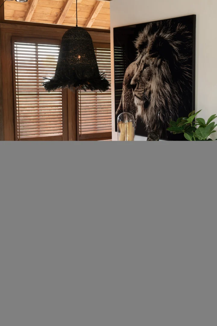 Sfeervolle interieurfoto: donkerbruin mangohout, lamp met veren, leeuwenprint.
