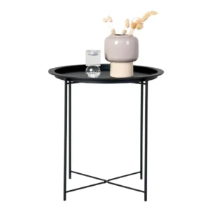 De Bastia Bijzettafel, een ronde bijzettafel van zwart gepoedercoat staal, heeft dunne gekruiste metalen poten en biedt plaats aan een beige vaas met gedroogde planten, een klein glas water en een rond glazen object.