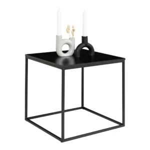 De Vita Sidetable, een bijzettafel van 45x45x45 cm met een strak zwart frame en blad, is gestyled met twee decoratieve kandelaars - een witte, een zwarte - elk met een witte kaars en gedroogde bloemen.