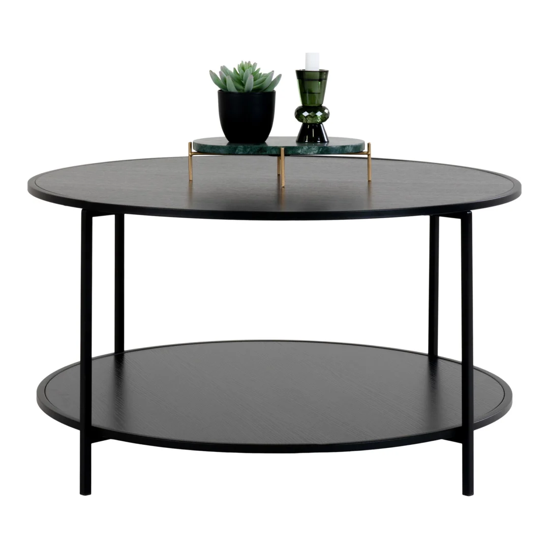 De Salontafel Zwart 80 x 45 CM Rond, gemaakt van spaanplaat, heeft een modern rond ontwerp met dunne metalen pootjes, een onderste plank en is gestyled met een groene kaarsenhouder, een kleine vetplant in pot en een decoratief dienblad bovenop.