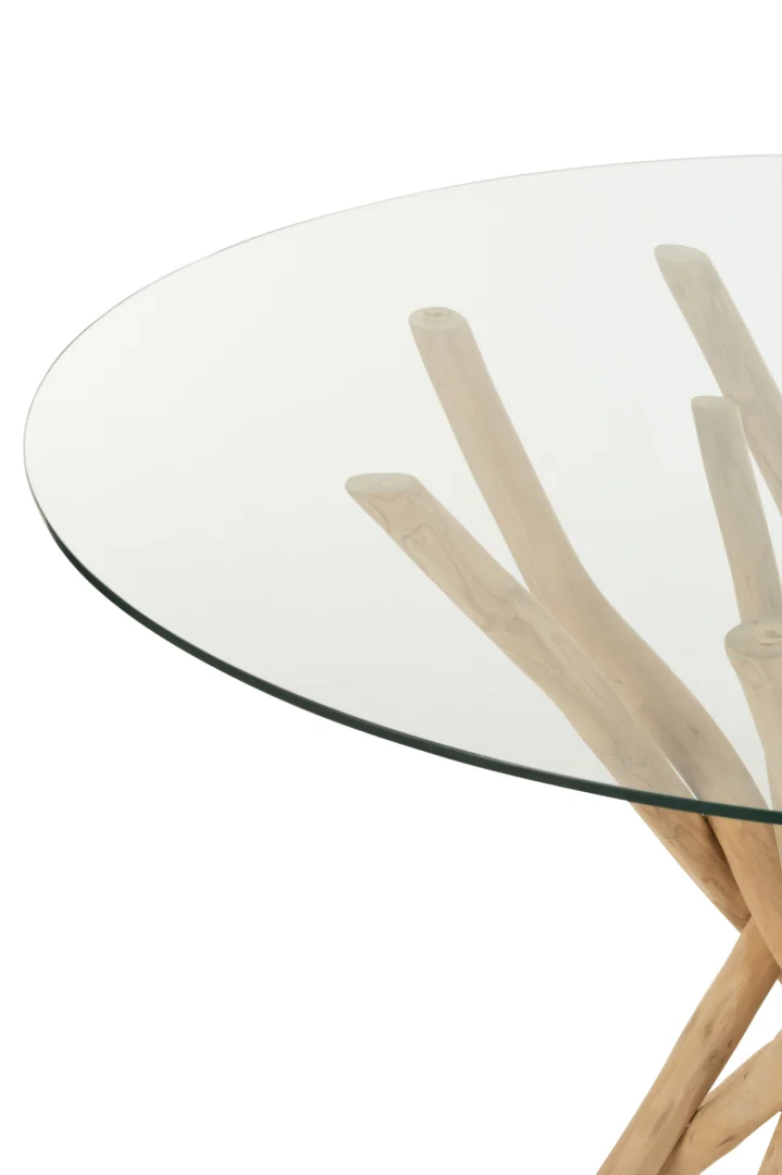 De Eettafel Branches Rond Teakhout Natuurlijk/Glas heeft een rond glazen tafelblad dat wordt ondersteund door een sculpturaal onderstel van natuurlijk teakhout met meerdere takvormige poten.