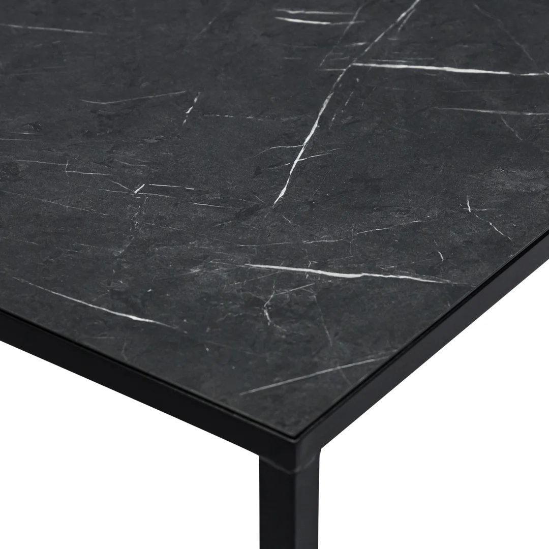 Close-up van de Salontafel Zwart 67 x 44 CM Marmer: een zwart marmeren tafelblad met witte adering, geplaatst op een slank zwart metalen frame en poot voor een moderne minimalistische look.