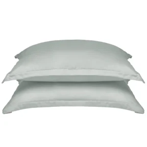 Twee gestapelde, lichtgrijze kussenslopen van Tencel lyocell op een witte achtergrond. Zachte belichting, effen stof zonder patroon.