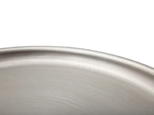 Close-up van de rand en het oppervlak van de Bijzettafel Antraciet, Zilver Ijzer, met de gladde, geborstelde metallic textuur tegen een witte achtergrond.