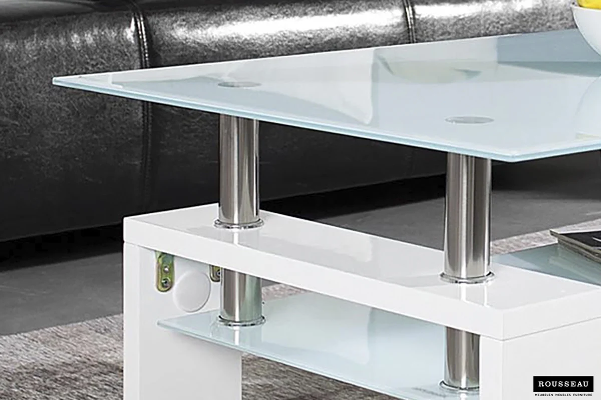 De Salontafel Wit Design Modern, een strakke glazen salontafel met metalen steunen en een glanzend wit onderstel, staat op een grijs vloerkleed voor een zwart leren bank. Het logo van het merk Rousseau staat rechtsonder.