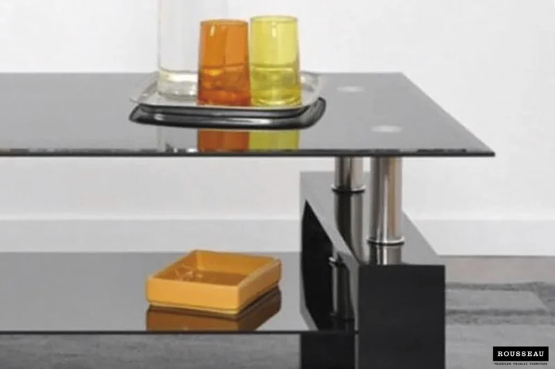 De Salontafel Zwart Tijdloos Design, met een modern glazen blad en metalen poten, toont een dienblad met drie kleurrijke glazen en een klein geel schaaltje op de onderste plank; het Rousseau-logo staat rechtsonder.