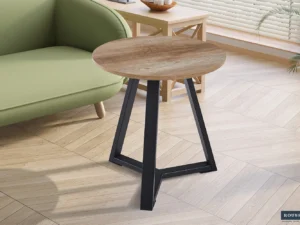 De bijzettafel 'Paso 2' Decor Old Oak, met een klein rond houten blad en zwarte metalen poten, staat naast een groene bank in een lichte kamer met houten vloer, moderne inrichting en zonlicht dat door de jaloezieën naar binnen schijnt.