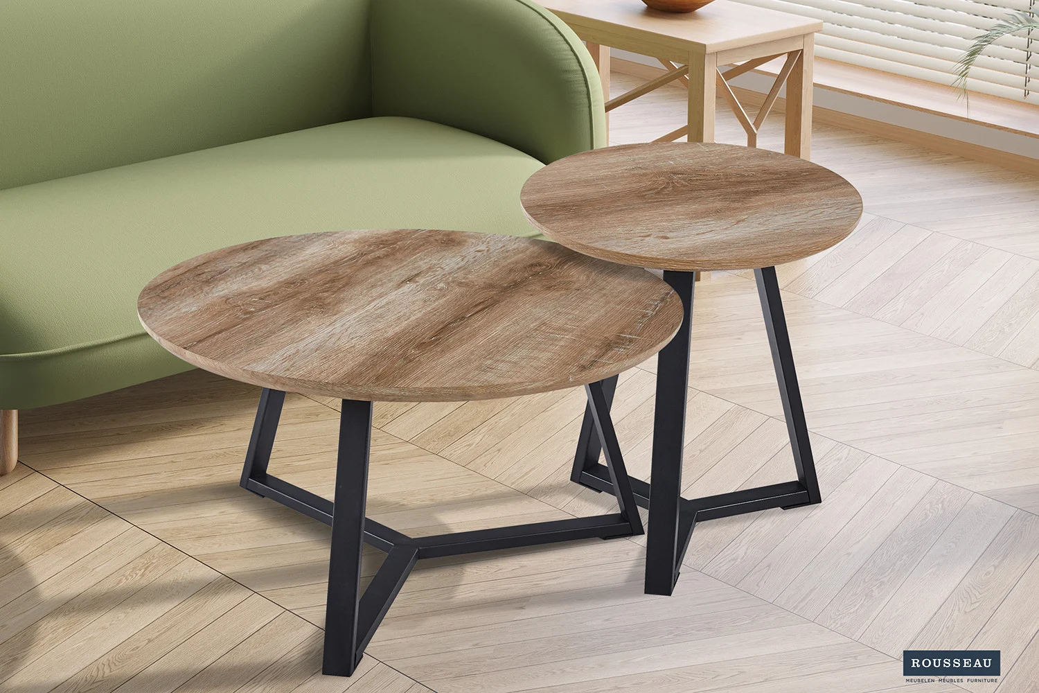Twee 'Paso 2' Decor Oud Eiken ronde bijzettafels met zwarte metalen poten staan naast een lichtgroene bank in een lichte kamer met een vloer met houtpatroon en een raam met jaloezieën.