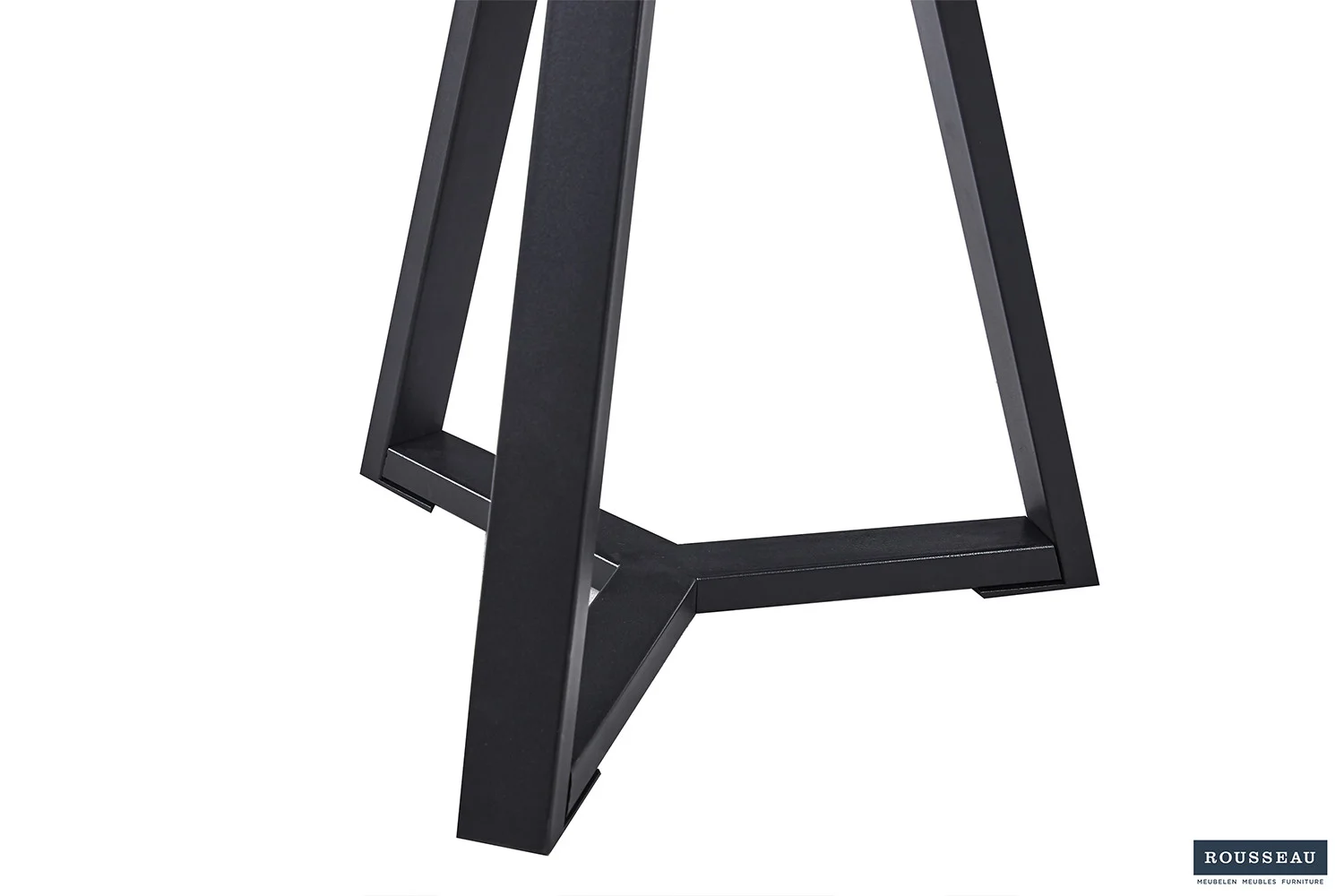 Een close-up van de zwarte metalen poten op de bijzettafel 'Paso 2' Decor Old Oak, die een driehoekig onderstel vormen. De achtergrond is egaal wit, met een klein Rousseau-logo in de rechterbenedenhoek.