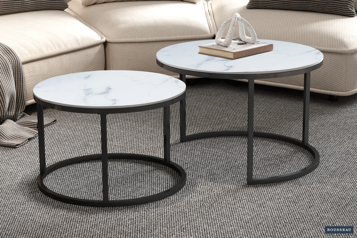 De Salontafel Wit Marmer Minimalistisch, met wit marmeren bladen en zwart metalen frames, staat op een grijs vloerkleed met textuur in een gezellige woonkamer met beige meubels en gestreepte kussens.