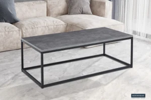 Een moderne woonkamer toont de Salontafel Grijs, Roest Steen: een eenvoudige rechthoekige salontafel met een grijs steenachtig blad en een zwart metalen onderstel, geplaatst op een lichtgrijze marmeren vloer voor een beige bank.